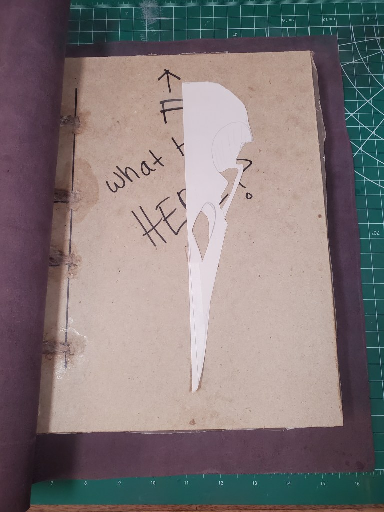 A paper cutout of the raven skull on the bookboard of the unfinished book.