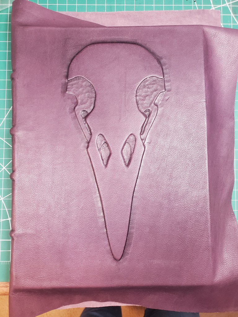 Purple leather is smoothed over raven skull emboss